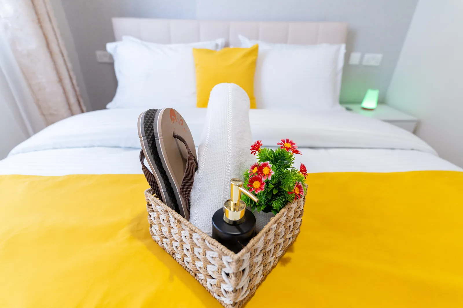 Guest welcome basket with towels and slippers on the made-up bed